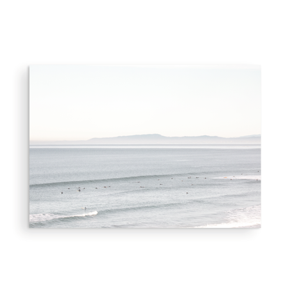 Coastal photography featuring a calm ocean scene with gentle waves and a hazy horizon line, predominantly in blue and white tones. Photograph in minimalist mock up.