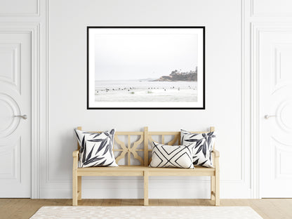 Landscape coastal photography of Salt Creek Beach with dark rocks on the shore and numerous surfers in the ocean. A neutral ocean print perfect for beach house decor. Photograph in minimalist mock up.
