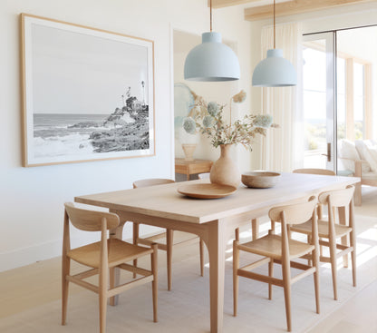 Fine art of WindanSea Beach, La Jolla California horizontal landscape black and white print by Southern California photographer Kim Dybczak of Salt Creek Prints, featuring a powerful waves crashing against the rocky shore of California coast. Beach homes and palm trees sit atop the cliffside, with stairs leading down to a sheltered area. Photograph in minimalist dining room mock up
