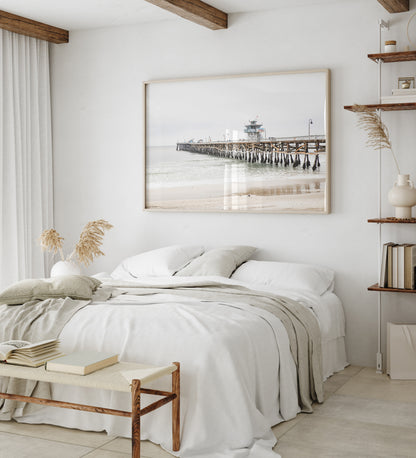 A long wooden pier, the San Clemente Pier, extends into the ocean in this landscape coastal photography. The beach in the foreground suggests a calm ocean print, ideal for a large coastal wall art or a beach cottage wall decor. Photograph in minimalist mock up.