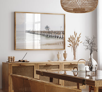 A long wooden pier, the San Clemente Pier, extends into the ocean in this landscape coastal photography. The beach in the foreground suggests a calm ocean print, ideal for a large coastal wall art or a beach cottage wall decor. Photograph in minimalist mock up.