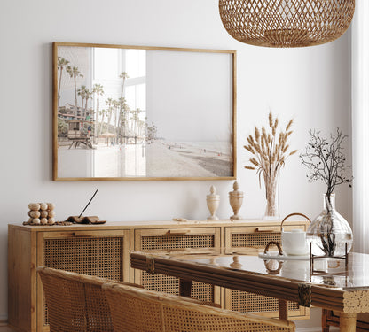 A wide landscape coastal photography view of San Clemente State Beach in Southern California, featuring a row of tall palm trees, a lifeguard tower, and people enjoying the calm beach. This horizontal image evokes Summer Vibes Wall Art and tropical beach print aesthetics. Photograph in minimalist mock up.