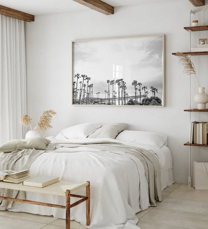Horizontal black and white coastal photography of many palm trees in the foreground, with the San Clemente Pier extending into the ocean in the background. This large landscape beach art conveys strong beach vibes. Photograph in minimalist mock up.