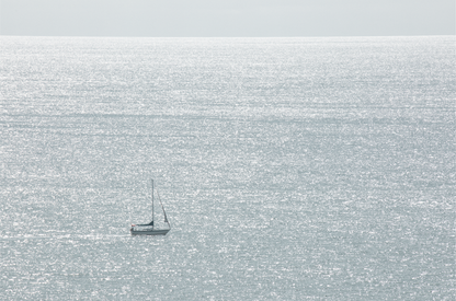 Large minimalist ocean print showing a smooth seascape with gentle ocean waves meeting a clear horizon line, one single sail boat in the distance. This calm nautical print provides a serene view in Dana Point, San Diego, California.