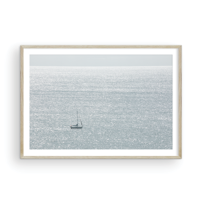 Large minimalist ocean print showing a smooth seascape with gentle ocean waves meeting a clear horizon line, one single sail boat in the distance. This calm nautical print provides a serene view in Dana Point, San Diego, California. Photograph in minimalist mock up.