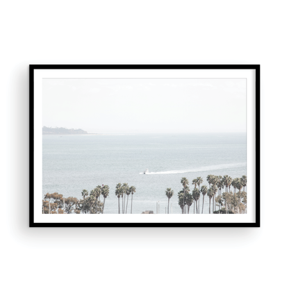 Landscape San Diego beach print showing a seascape with a boat gliding on the water with palm trees in the foreground. Photograph in minimalist mock up.