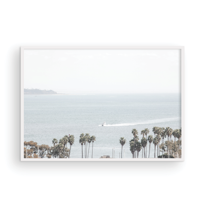 Landscape San Diego beach print showing a seascape with a boat gliding on the water with palm trees in the foreground. Photograph in minimalist mock up.