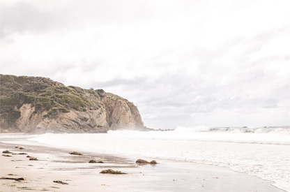 Minimalist ocean print of ocean waves and large sandy cliffs in the distance overlooking the seascape. 