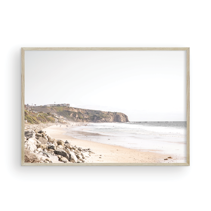Minimalist ocean print of ocean waves with beach goers in the distance and large  sandy cliffs in the distance overlooking the seascape. Photograph in minimalist mock up.