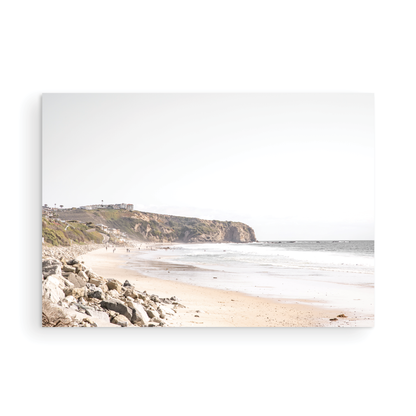 Minimalist ocean print of ocean waves with beach goers in the distance and large  sandy cliffs in the distance overlooking the seascape. Photograph in minimalist mock up.