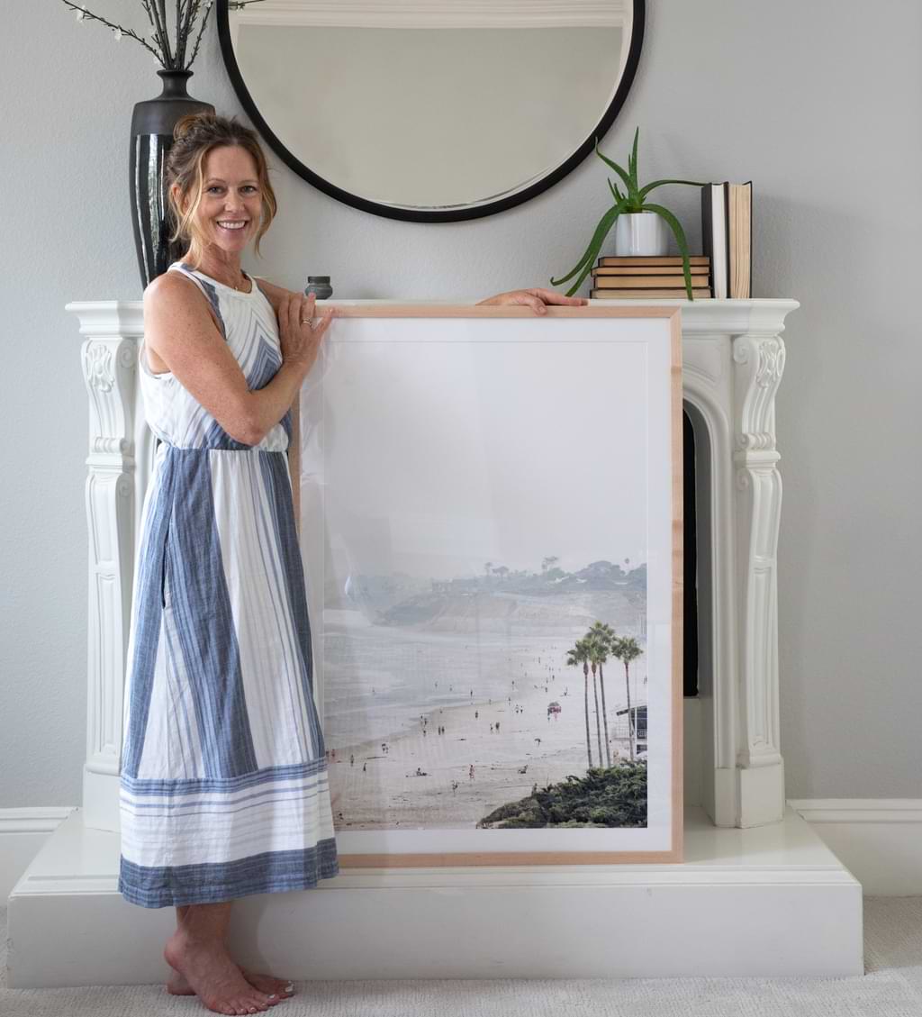 Kim Dybczak posing with framed coastal print.