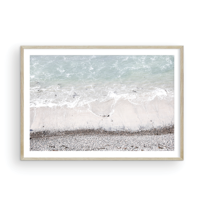 Horizontal surf print of a rocky beach next to foamy ocean waves. This surfing art captures a unique coastline. Photograph in minimalist mock up.