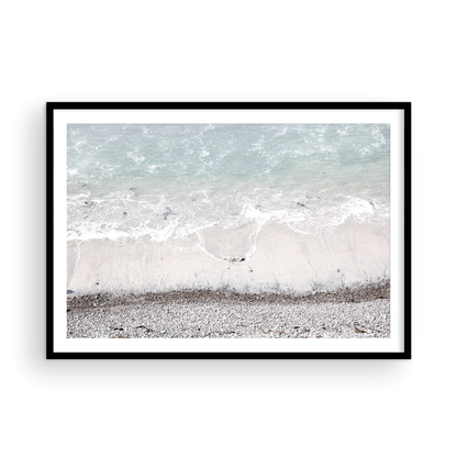 Horizontal surf print of a rocky beach next to foamy ocean waves. This surfing art captures a unique coastline. Photograph in minimalist mock up.