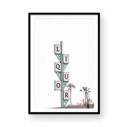 A vertical shot of the iconic Leucadia Liquor sign, with each letter of "LIQUOR" in a separate box against a teal-colored post and a bright white sky with palm trees in the background. Photograph in minimalist mock up