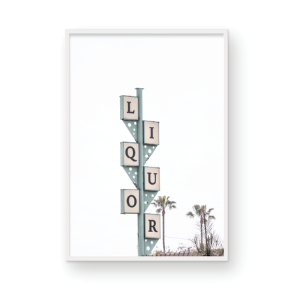 A vertical shot of the iconic Leucadia Liquor sign, with each letter of "LIQUOR" in a separate box against a teal-colored post and a bright white sky with palm trees in the background. Photograph in minimalist mock up