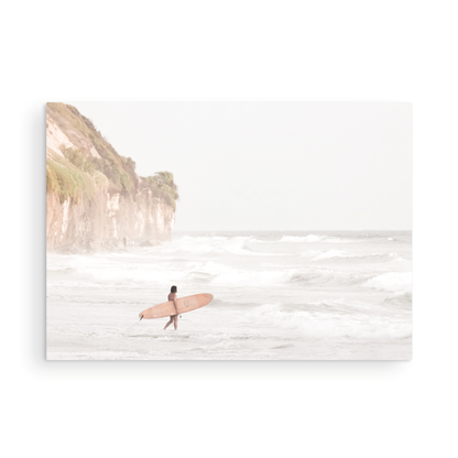 Horizontal surf art print of a lone surfer carrying a surfboard, walking on a rocky, foggy shoreline at Moonlight State Beach with a cliff in the background. Photograph in minimalist mock up.