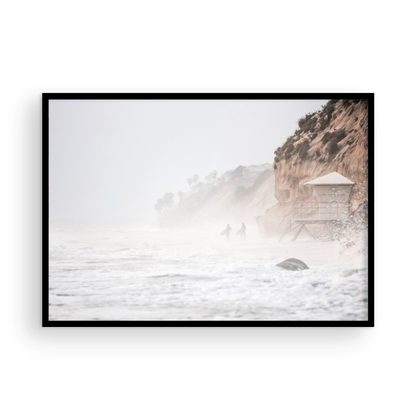 Hazy surf art of two surfers running into stormy ocean waves at Moonlight State Beach, with a lifeguard tower and cliff disappearing into the fog. A dramatic seascape print. Photograph in minimalist mock up