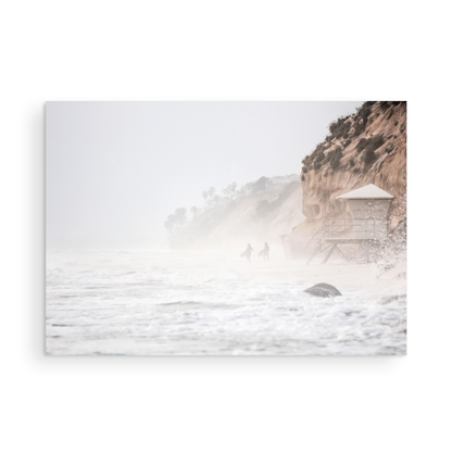Hazy surf art of two surfers running into stormy ocean waves at Moonlight State Beach, with a lifeguard tower and cliff disappearing into the fog. A dramatic seascape print. Photograph in minimalist mock up