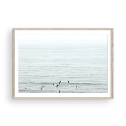 Horizontal surf art showing multiple surfers waiting in the calm ocean water for waves, with a hazy Southern California coastline in the distance. This minimalist surf print captures authentic surf vibes. Photograph in minimalist mock up.