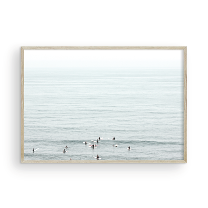 Horizontal surf art showing multiple surfers waiting in the calm ocean water for waves, with a hazy Southern California coastline in the distance. This minimalist surf print captures authentic surf vibes. Photograph in minimalist mock up.