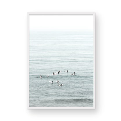 Vertical surf art showing multiple surfers waiting in the calm ocean water for waves, with a hazy Southern California coastline in the distance. This minimalist surf print captures authentic surf vibes. Photograph in minimalist mock up.