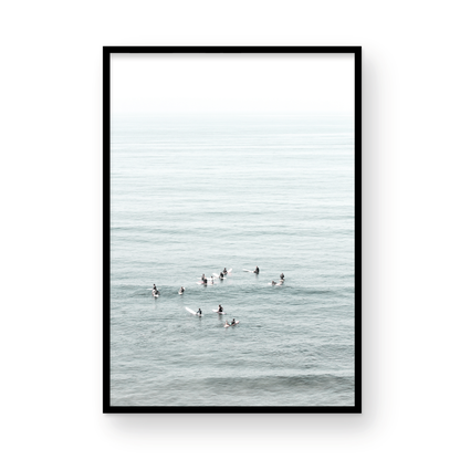 Vertical surf art showing multiple surfers waiting in the calm ocean water for waves, with a hazy Southern California coastline in the distance. This minimalist surf print captures authentic surf vibes. Photograph in minimalist mock up.