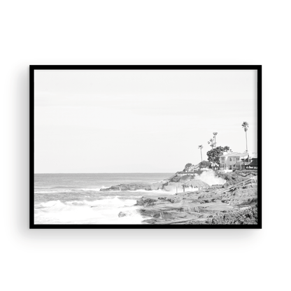 Fine art of WindanSea Beach, La Jolla California horizontal landscape black and white print by Southern California photographer Kim Dybczak of Salt Creek Prints, featuring a powerful waves crashing against the rocky shore of California coast. Beach homes and palm trees sit atop the cliffside, with stairs leading down to a sheltered area. Photograph in minimalist mock up