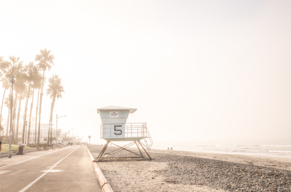 Landscape lifeguard tower photography of Oceanside, California, showing lifeguard tower number 5 on the beach with palm trees and a pathway leading towards the ocean.