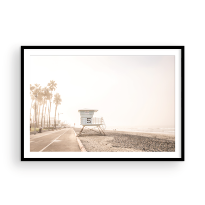 Landscape lifeguard tower photography of Oceanside, California, showing lifeguard tower number 5 on the beach with palm trees and a pathway leading towards the ocean. Photograph in minimalist mock up.