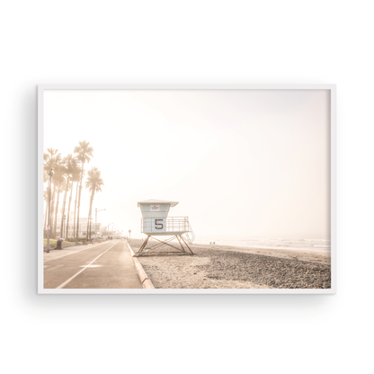 Landscape lifeguard tower photography of Oceanside, California, showing lifeguard tower number 5 on the beach with palm trees and a pathway leading towards the ocean. Photograph in minimalist mock up.
