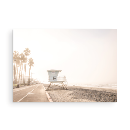 Landscape lifeguard tower photography of Oceanside, California, showing lifeguard tower number 5 on the beach with palm trees and a pathway leading towards the ocean. Photograph in minimalist mock up.