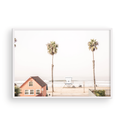 Landscape beach photography of Oceanside, California, highlighting a beachfront house and a lifeguard tower with two tall palm trees and the ocean. Photograph in minimalist mock up.