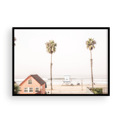 Landscape beach photography of Oceanside, California, highlighting a beachfront house and a lifeguard tower with two tall palm trees and the ocean. Photograph in minimalist mock up.