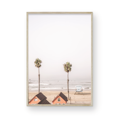 Vertical coastal photography of Oceanside, California, showing beachfront houses and a lifeguard tower with two prominent palm trees overlooking the ocean. A minimalist surf print. Photograph in minimalist mock up.