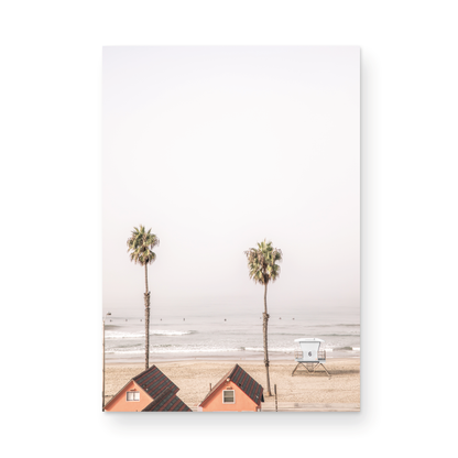 Vertical coastal photography of Oceanside, California, showing beachfront houses and a lifeguard tower with two prominent palm trees overlooking the ocean. A minimalist surf print. Photograph in minimalist mock up.