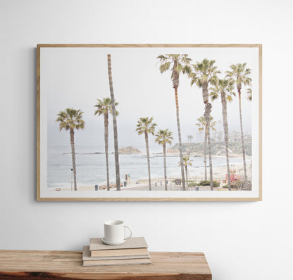 Horizontal coastal photography of a beachscape at Laguna Beach, California, beach art print featuring palm trees and a clear blue sky with a few clouds over a beach scene. Photograph in minimalist mock up.