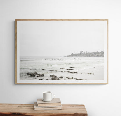 Landscape coastal photography of Salt Creek Beach with dark rocks on the shore and numerous surfers in the ocean. A neutral ocean print perfect for beach house decor. Photograph in minimalist mock up.