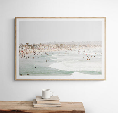 Landscape beach photography of a busy San Diego public beach with many people in the sand and ocean waves, a true summer vibes scene. Photograph in minimalist mock up.