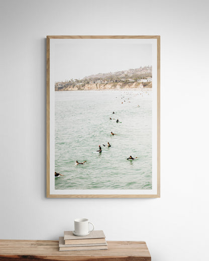 Vertical surf print showing several surfers paddling in the ocean at Pacific Beach, with a distant coastline. This image captures the surfing art of Southern California. Photograph in minimalist mock up.