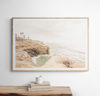 Fine art of Sunset Cliffs, San Diego California horizontal print of hazy high-angle landscape beach photography captures a light blue ocean meeting tall tan, rocky, brown cliffs rise as iconic coastal scenery. Photograph in minimalist mock up.
