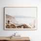 Captivating San Diego coast scene, presented as horizontal beach art. This piece of travel photography features a prominent bridge extending over a wide sandy beach with calm ocean waves. A coastal road winds along the base of rugged cliffs, with a lone coastal palm tree adding a touch of tropical essence to this Southern California seascape print. Photograph in minimalist mock up