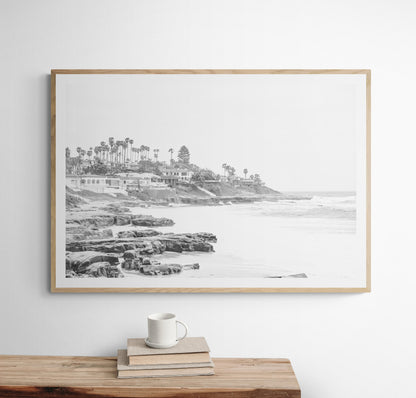 Fine art of WindanSea Beach, La Jolla California horizontal landscape black and white print by Southern California photographer Kim Dybczak of Salt Creek Prints, featuring a powerful waves crashing against the rocky shore of California coast. Beach homes and palm trees sit atop the cliffside, with stairs leading down to a sheltered area. Photograph in minimalist framed mock up