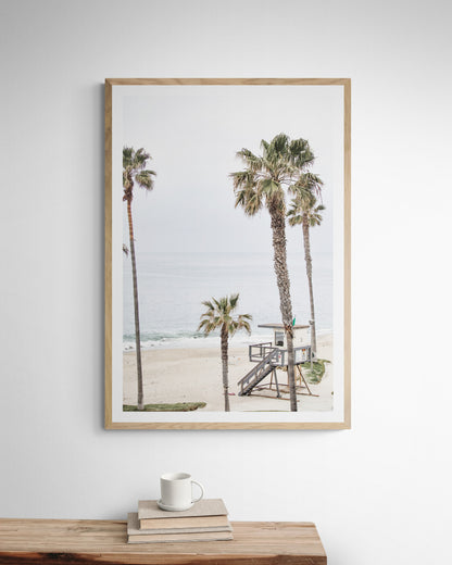 Vertical coastal photography of a coastal scene with palm trees and a lifeguard tower at Aliso Beach, Laguna California, with a wooden frame. Photograph in minimalist mock up.
