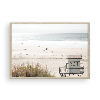 Landscape coastal photography of Salt Creek Beach Park featuring a lifeguard tower (SC 1) on the sand, with distant figures and ocean waves. This beachscape print has a calming vibe. Photograph in minimalist mock up.