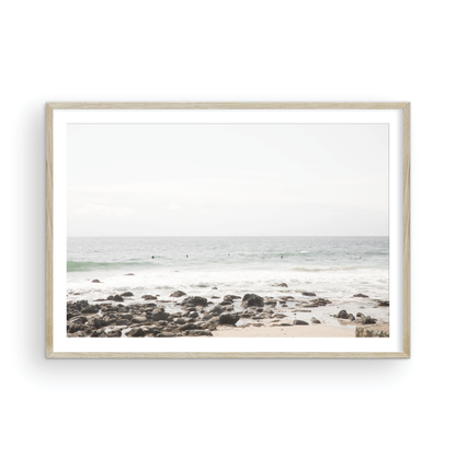 Landscape coastal photography of Salt Creek Beach with dark rocks on the shore and numerous surfers in the ocean. A neutral ocean print perfect for beach house decor. Photograph in minimalist mock up.