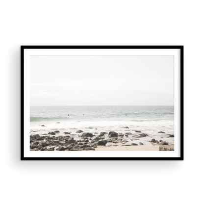 Landscape coastal photography of Salt Creek Beach with dark rocks on the shore and numerous surfers in the ocean. A neutral ocean print perfect for beach house decor. Photograph in minimalist mock up.