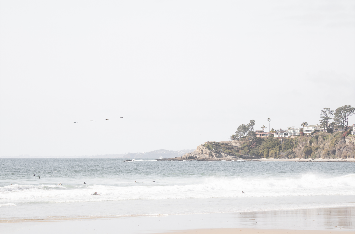 Landscape surf wall decor featuring surfers in the ocean near Salt Creek Beach, with a distant residential coastline and crashing waves. This print captures the surf vibes. 