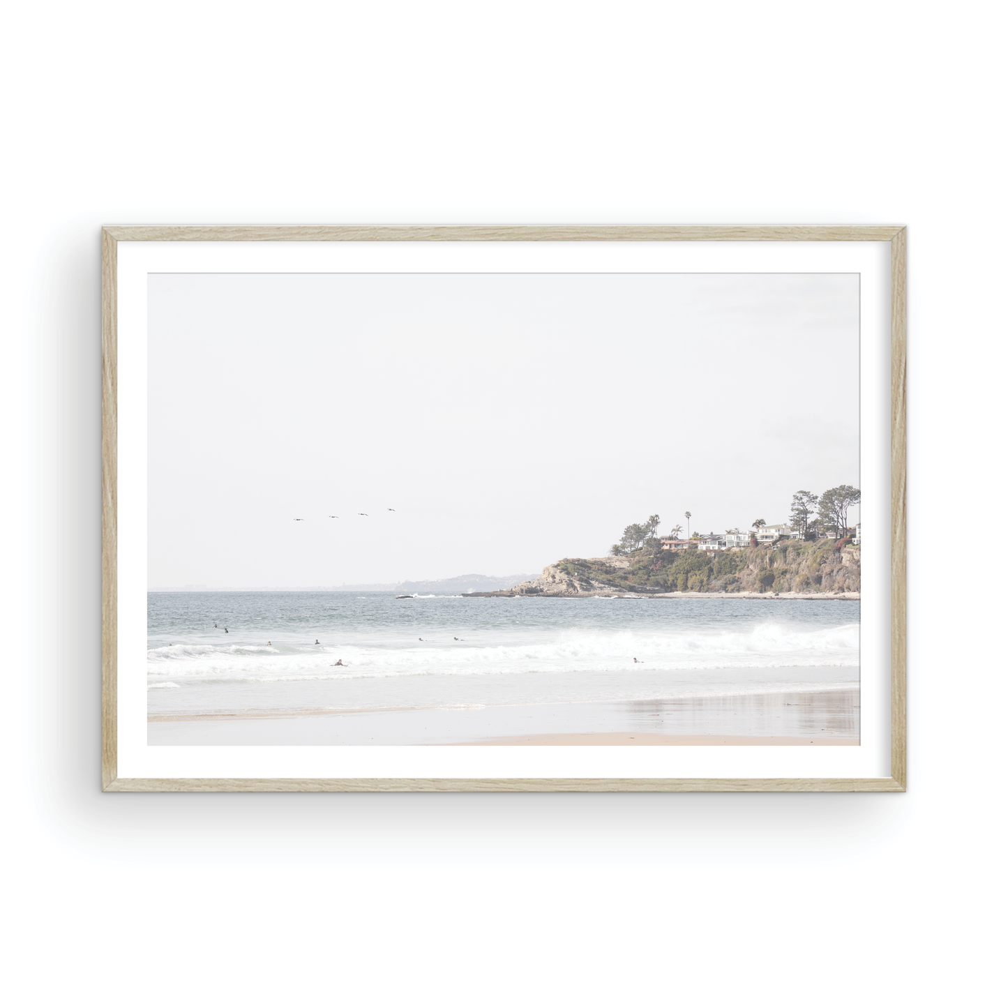 Landscape surf wall decor featuring surfers in the ocean near Salt Creek Beach, with a distant residential coastline and crashing waves. This print captures the surf vibes. Photograph in minimalist mock up.