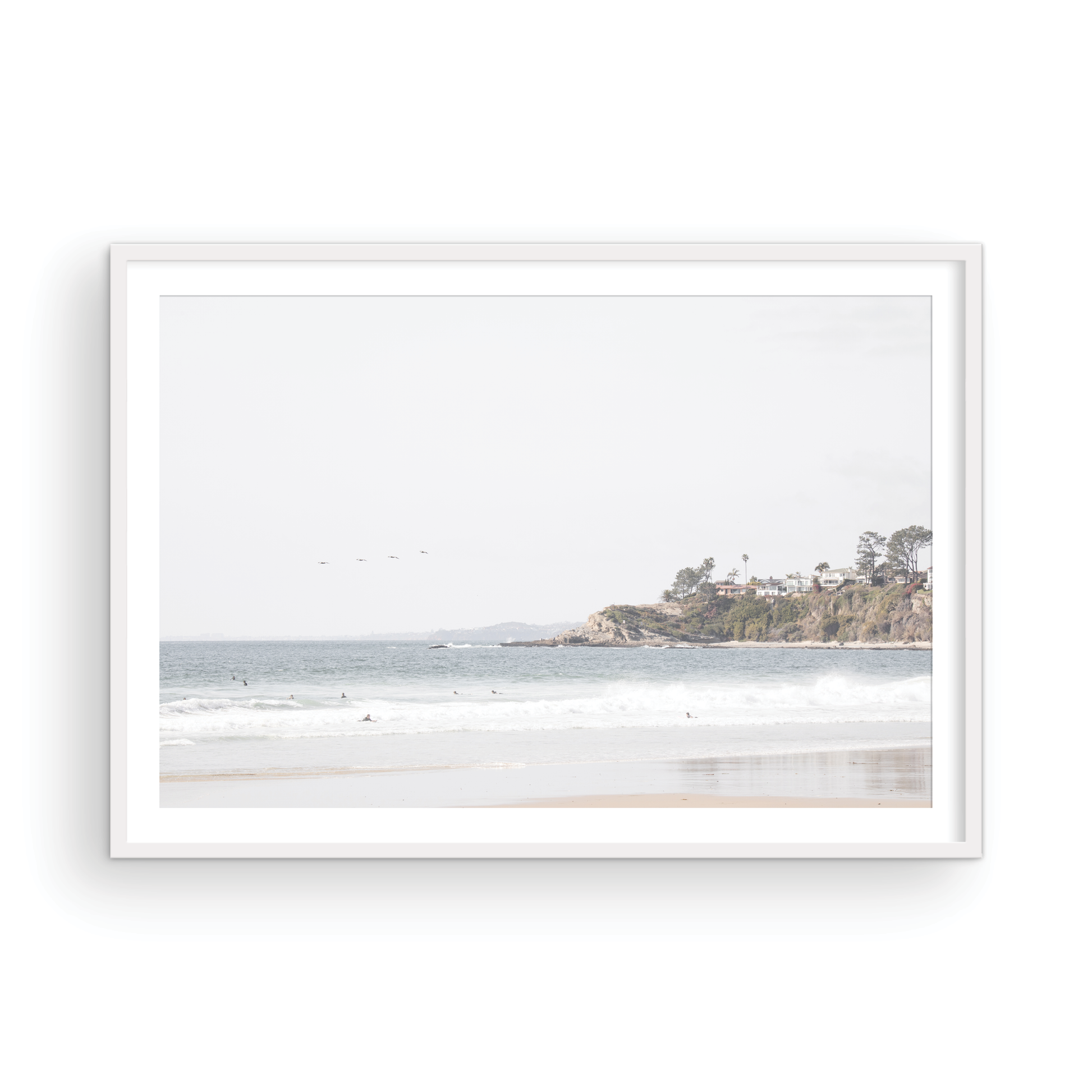 Landscape surf wall decor featuring surfers in the ocean near Salt Creek Beach, with a distant residential coastline and crashing waves. This print captures the surf vibes. Photograph in minimalist mock up.