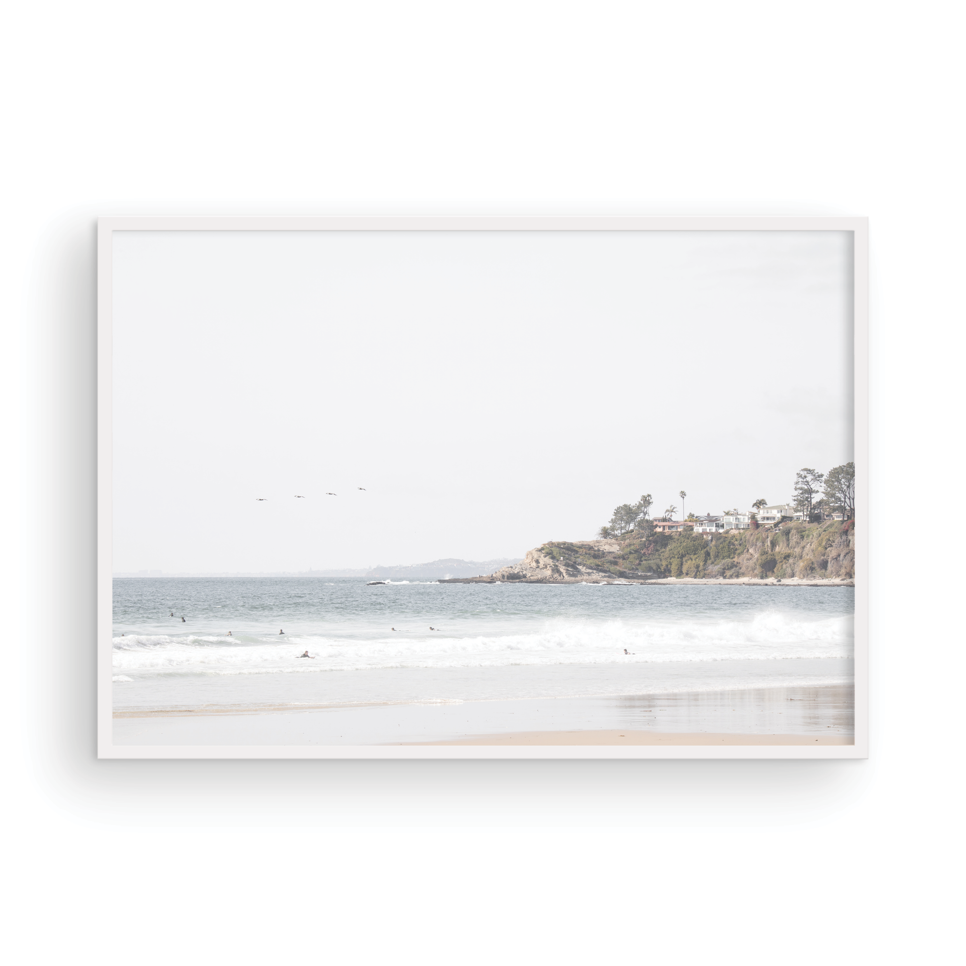 Landscape surf wall decor featuring surfers in the ocean near Salt Creek Beach, with a distant residential coastline and crashing waves. This print captures the surf vibes. Photograph in minimalist mock up.